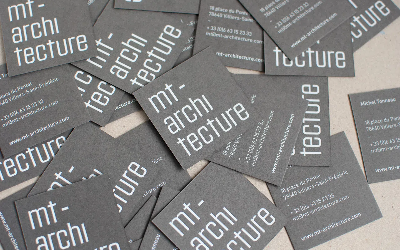 Photographie d’une vingtaine de cartes de visite de l’atelier MT-Architecture, disposées en vrac.