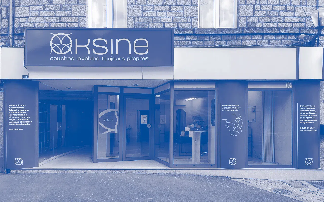 Photographie en monochrome bleu de la devanture du local commercial Oksine, situé dans le centre ville de Saint-James.